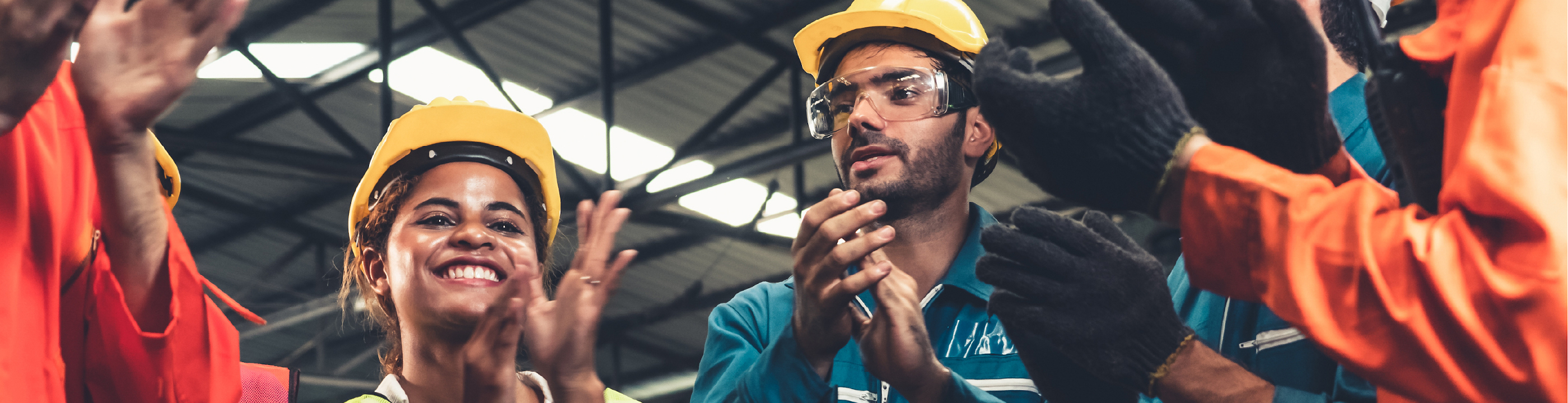 Diverse group of 5 construction workers in a circle clapping