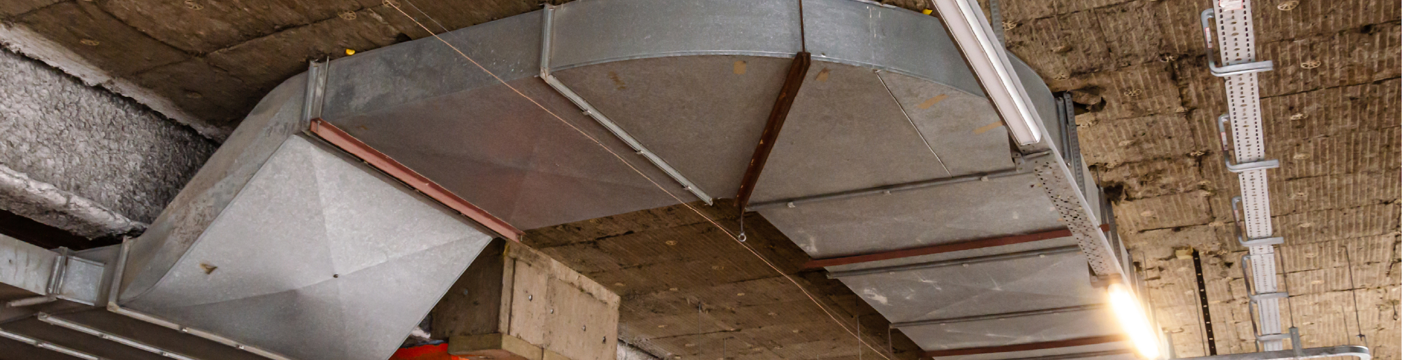 Open ceiling of a commercial building showing a large piece of ductwork