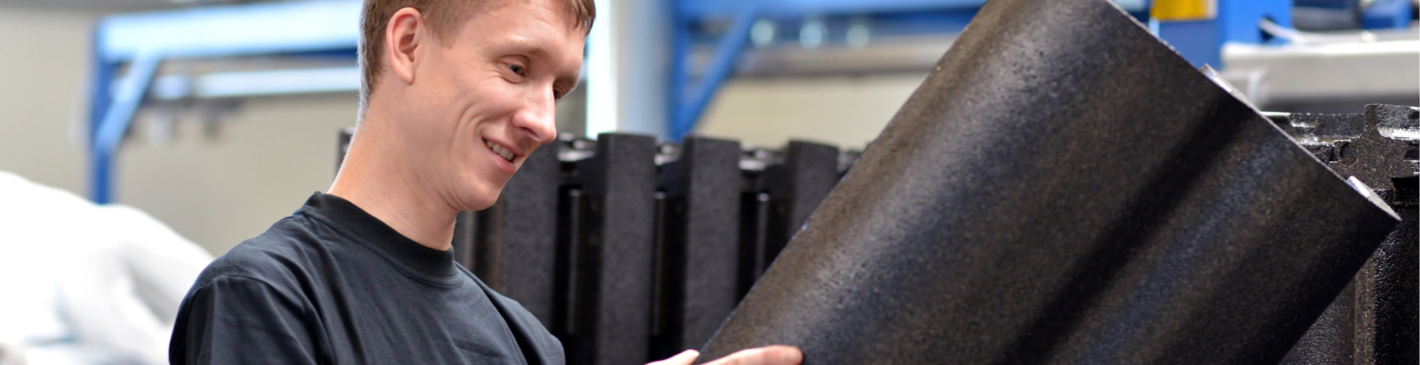 Hero image of a worker inspecting a peice of custom fabricated insulation infront of a stcok pile of completed insulation.