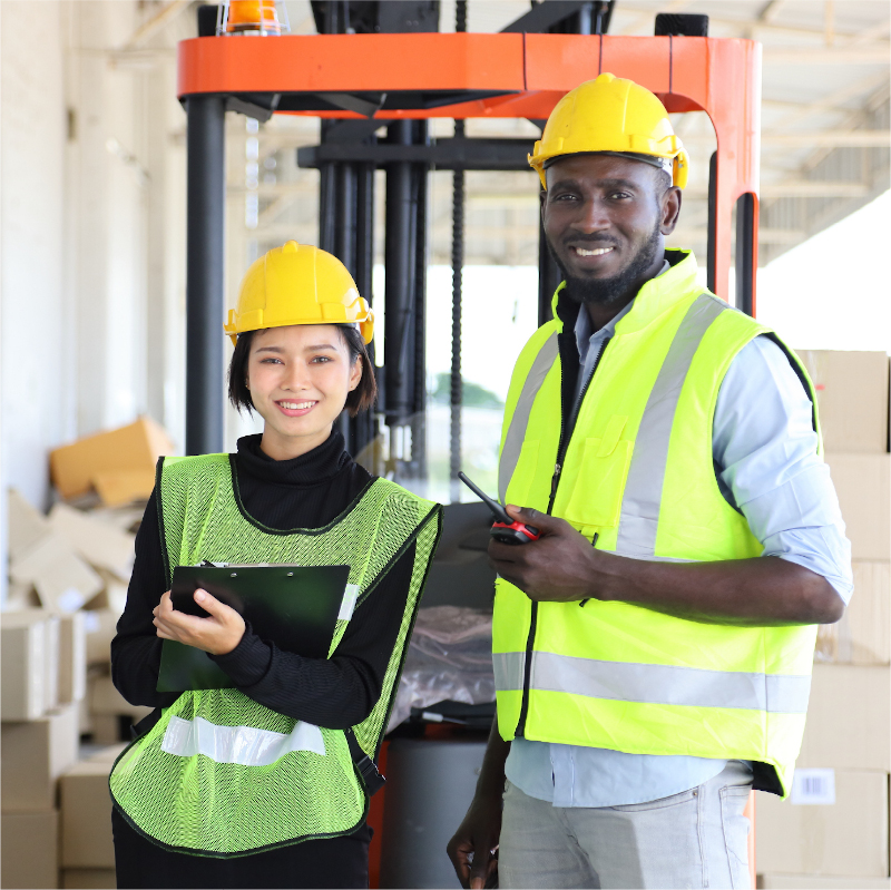 Multi-racial man and mowen in safety vests and hats in warehouse
