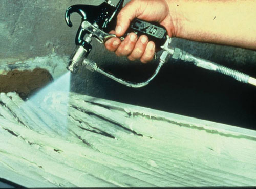 Photo of spray gun coating a cable tray of wires with insulation