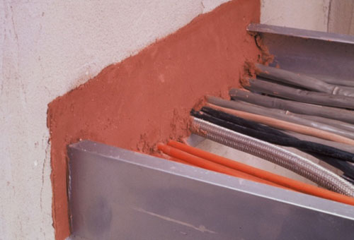 Photo of a wall penetrated by various wires, all sealed, with no openings